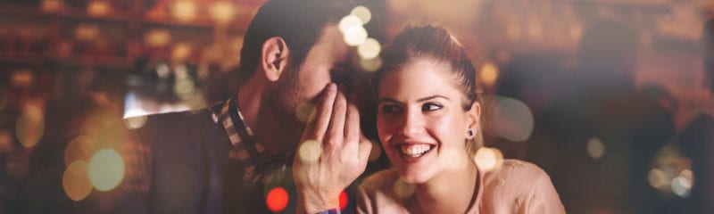 dating while separated; man whispering into young woman's ear while she smiles