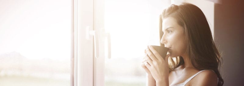 woman drinking coffee and staring out window