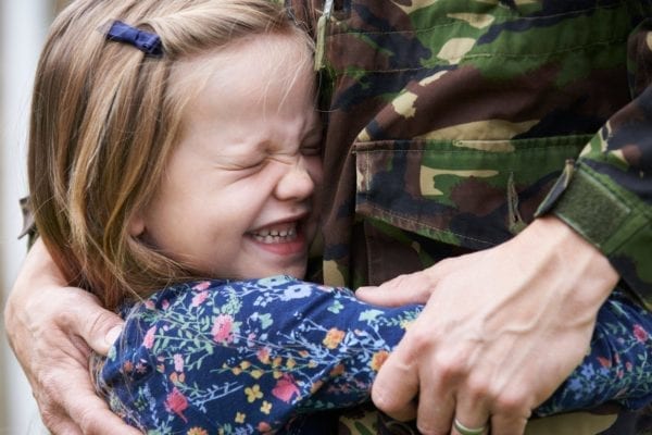 cute little girl tightly hugging man in military uniform